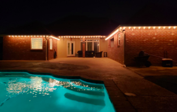 A reviewer's photo showing string lights along the roofline at the back of their house, above a pool patio area.