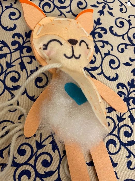 A felt fox with its body partly sewn, displaying its blue felt heart and stuffing