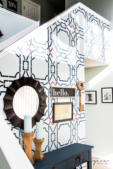 An entryway featuring a soft light blue backdrop with a bold, dark blue geometric stencil design that creates an eye-catching focal point.