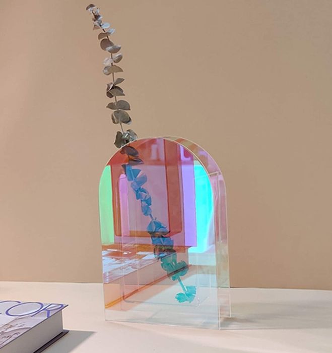 An arched vase with a single eucalyptus stem inside. Its shimmering, iridescent finish catches the light beautifully.