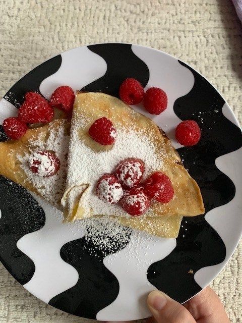 Crepes garnished with raspberries and a sprinkle of sugar