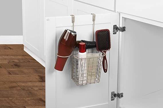 A wire organizer with a single basket and two circular slots, holding a blow dryer, a brush, and two hair care products, with space remaining for more.