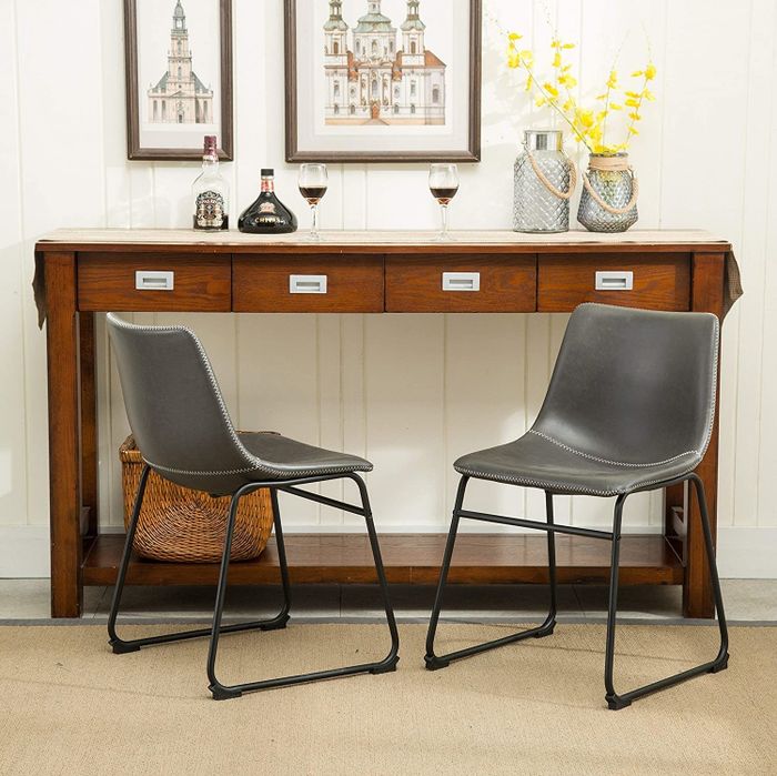 The gray leather armless chairs with black iron frame legs.