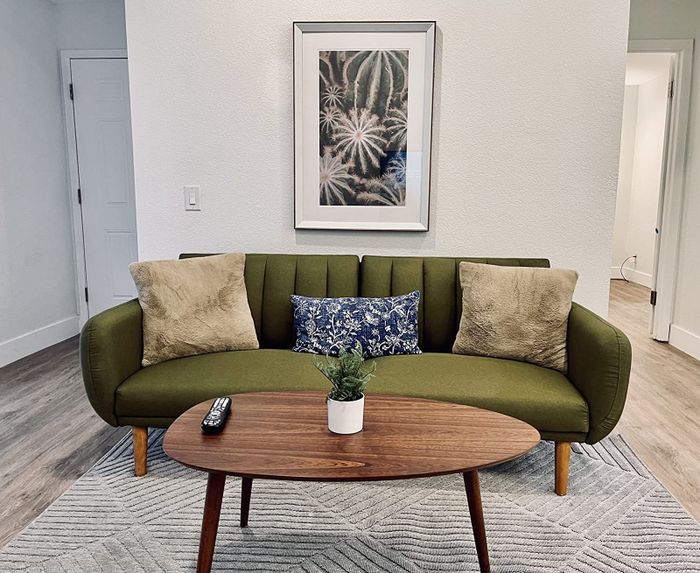 A reviewer’s walnut coffee table placed in front of a green sofa, offering a sleek and stylish accent to the living room.