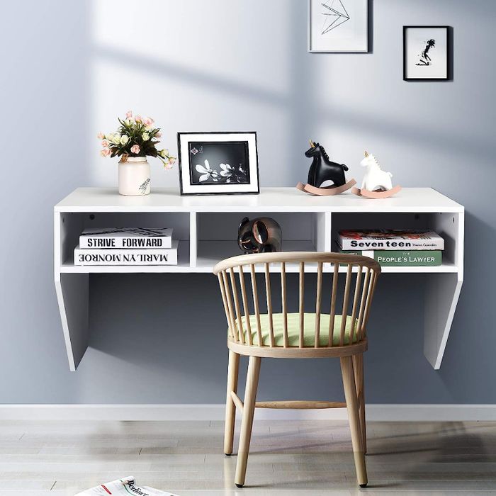 A white wall-mounted desk with built-in storage cubbies.