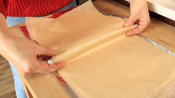 Hands carefully folding parchment paper.