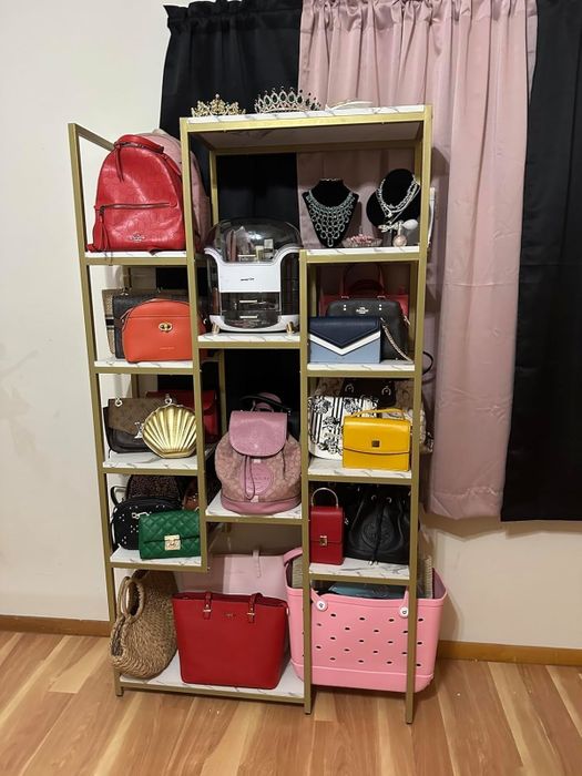 A display shelf showcasing an elegant assortment of handbags, a crown, and sparkling jewelry, including necklaces, all carefully organized to highlight a selection of luxurious accessories