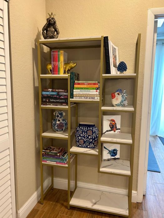 A bookshelf beautifully arranged with vibrant books, charming ceramic animal figurines, and stylish decorative pieces like a blue owl and a porcelain vase, nestled within a cozy home setting