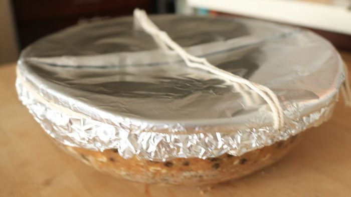 A bowl covered with foil, sealed tightly with string around the rim.