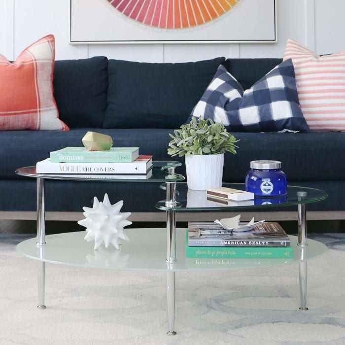A sleek translucent oval glass table with two clear, wave-like shelves on top, creating a modern and minimalist aesthetic.