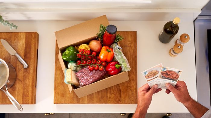 A box sitting on a kitchen counter filled with fresh ingredients ready for cooking.