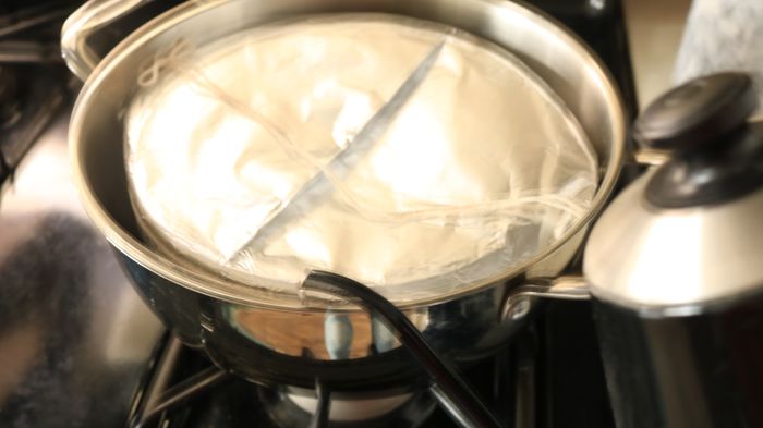A pot containing a bowl covered with foil.