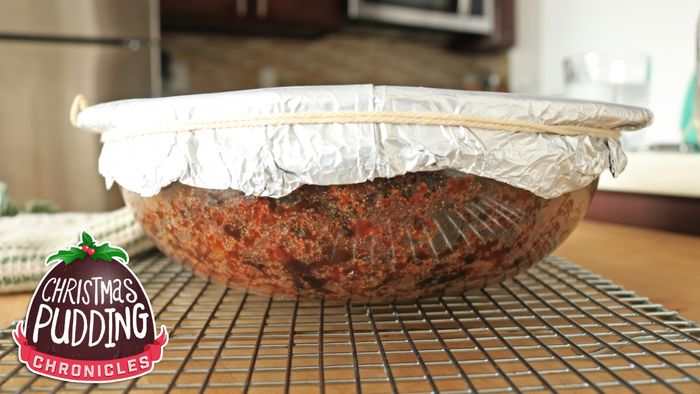 A glass bowl filled with cake batter, sealed with foil on top