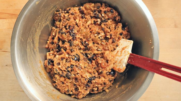A bowl filled with fruit cake batter and a spatula nearby.