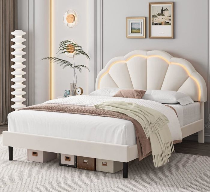 A modern bedroom with a sleek bed frame, a plush headboard, and artwork hanging on the wall