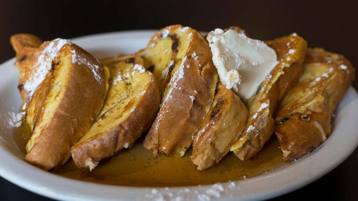 A plate of golden triangular French toast topped with a dollop of butter.