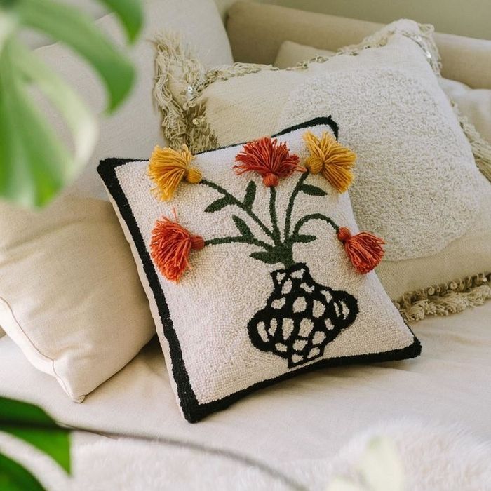 A square throw pillow featuring a decorative vase pattern and intricate three-dimensional flowers.