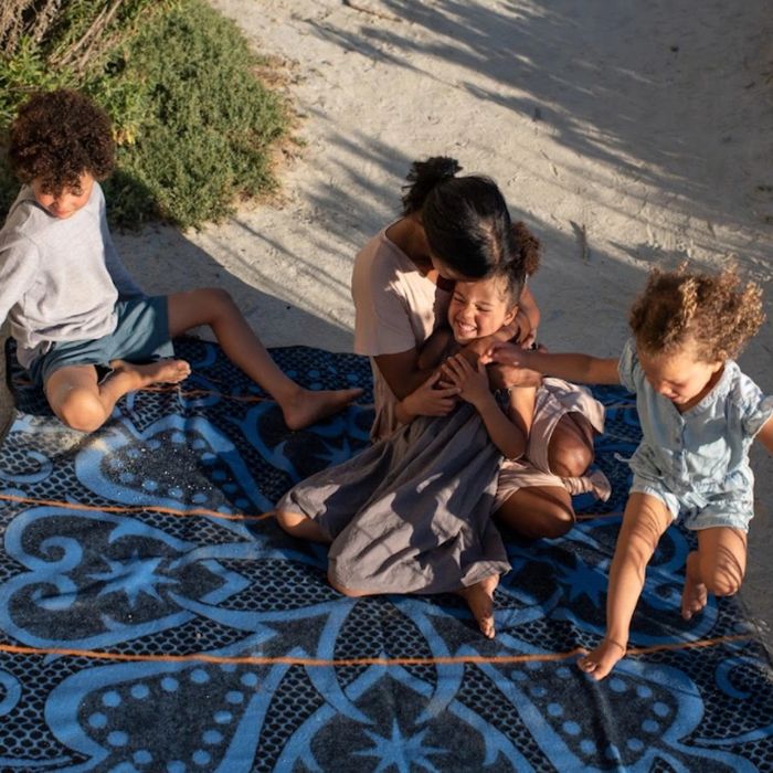 A family enjoying a day at the beach, playing on a blanket.
