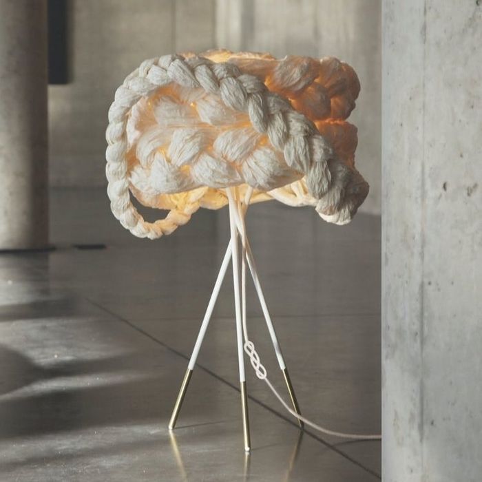 A standing lamp with three legs and a large, intricately knitted shade that adds a unique touch to any room.
