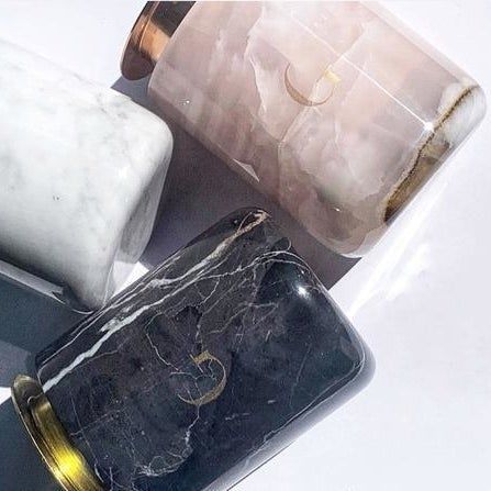 Candles housed in elegant marble jars with gold lids, exuding luxury and sophistication.