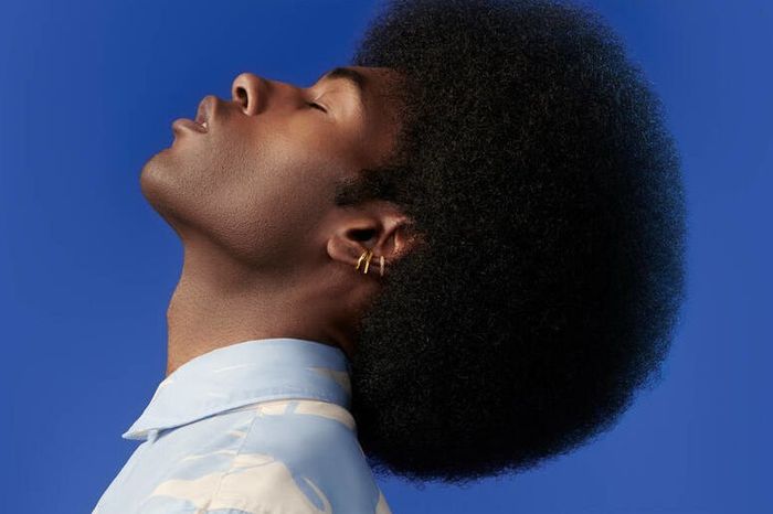 The model's head is tilted downward, highlighting three stylish cuff earrings in a striking display.