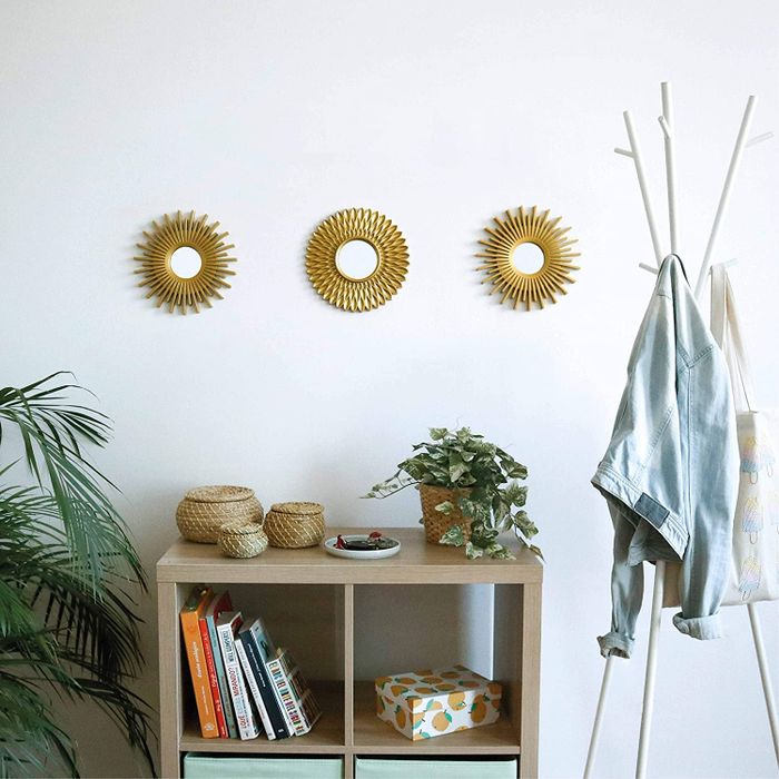 The gold starburst mirrors arranged over a bookshelf.