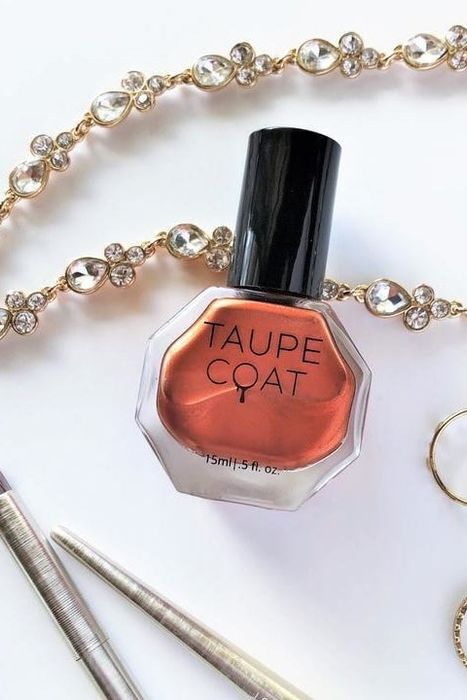 A bottle of nail polish resting on a table, surrounded by delicate jewelry pieces, showcasing a perfect balance of beauty and elegance.