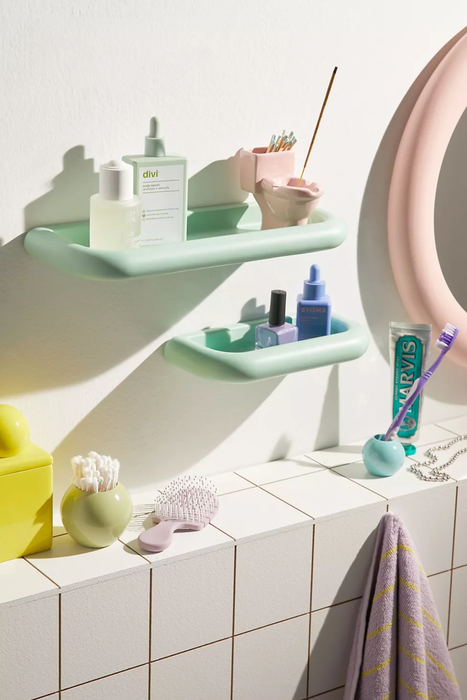 Two mint green shelves holding skincare products and nail polish.