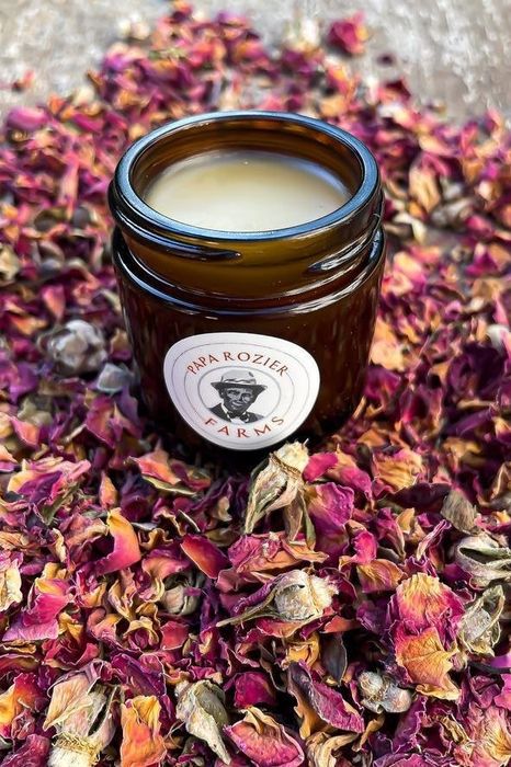 A rose balm nestled in an apothecary jar, with delicate rose petals surrounding it, creating a fragrant and soothing experience.
