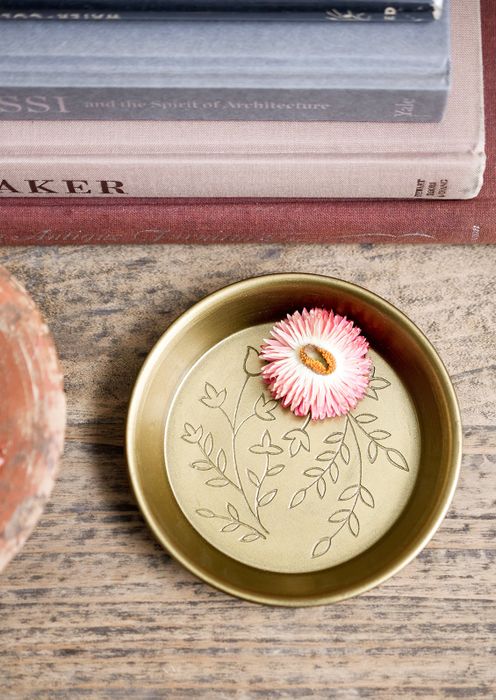 A brass catchall dish with intricate floral etching