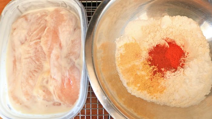 A bowl of buttermilk-marinated chicken alongside a mixture of flour and spices.