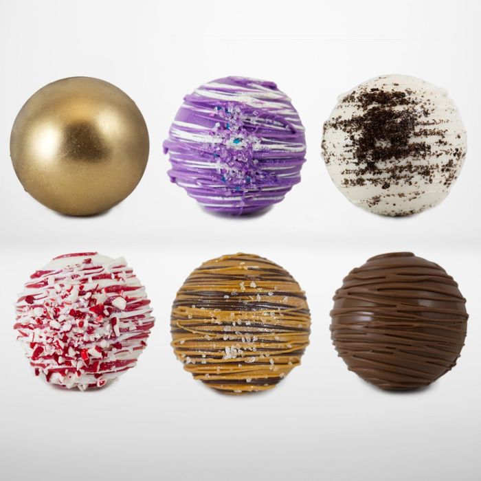 Six chocolate balls, each topped with festive decorations, perfect for the holiday season.