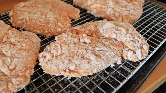 Raw chicken cutlets coated in a textured breading.