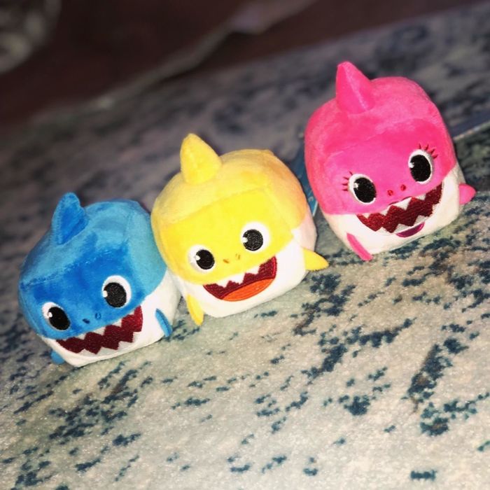 A photo from the reviewer showing the blue, yellow, and pink shark plush toys.