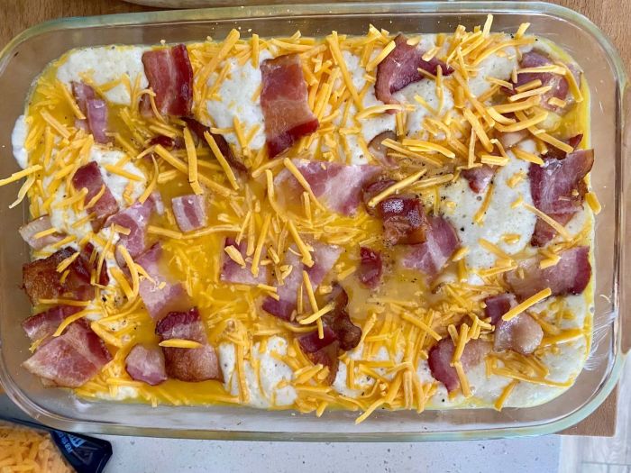 A casserole dish layered with pancake batter, eggs, bacon, and cheese, ready to be baked to perfection.