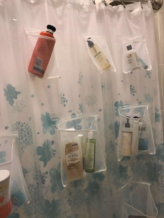 A reviewer photo showing the shower curtain with bath products neatly arranged in the mesh pockets.