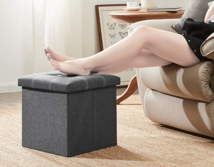 A model resting their feet on the grey cube storage ottoman
