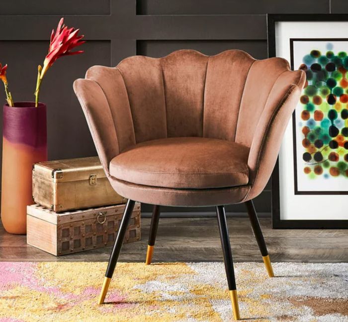 A velvet seashell-shaped chair with sleek black and gold legs, perfect for adding a touch of luxury to any space.