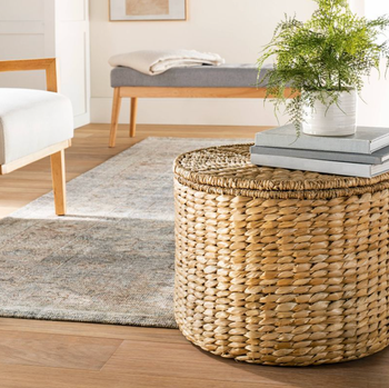 The seagrass storage ottoman with books and a plant placed on top