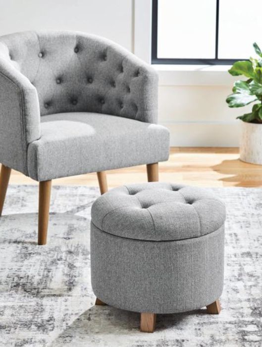 A tufted, circular grey storage ottoman.