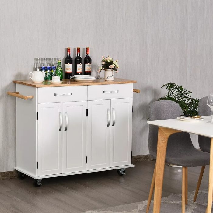 The rolling kitchen island in white, topped with wine, plates, drinks, and various accessories.