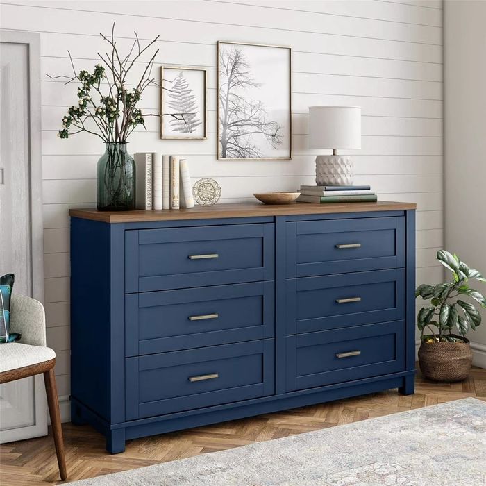 The navy dresser adorned with a lamp and decorative items on top.