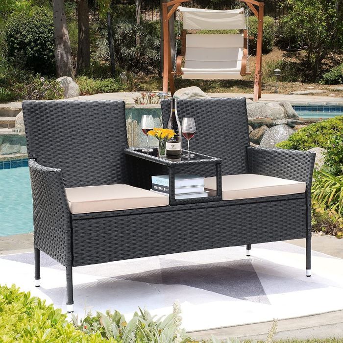 A chaise lounge with a built-in center table, placed by a poolside.
