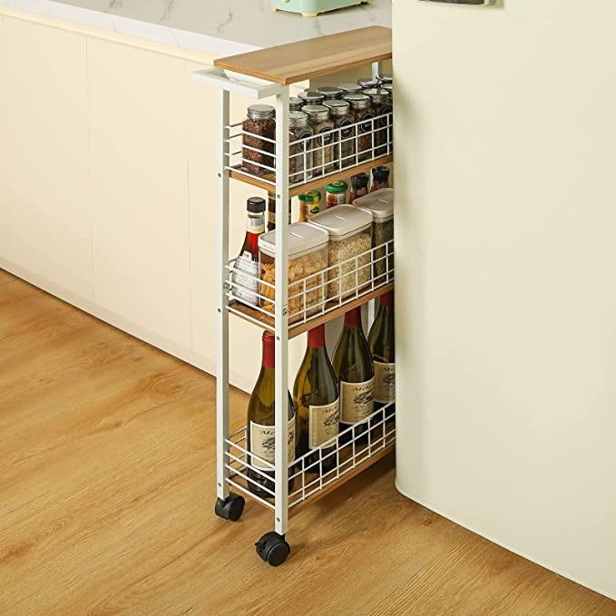 A slim white cart neatly stored in the tight space between the kitchen counter and fridge.