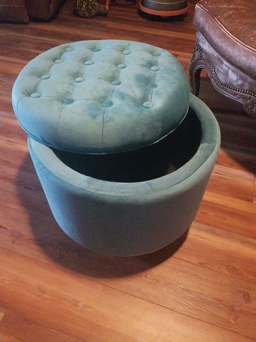 The blue storage ottoman with its lid slightly ajar, offering a peek at the spacious interior for storing various items.