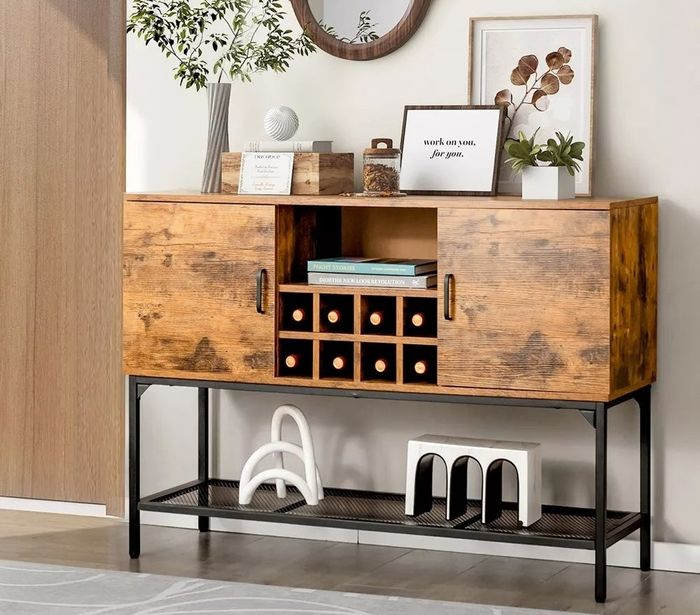 A wooden kitchen buffet, beautifully displaying wine bottles, photos, houseplants, and books.