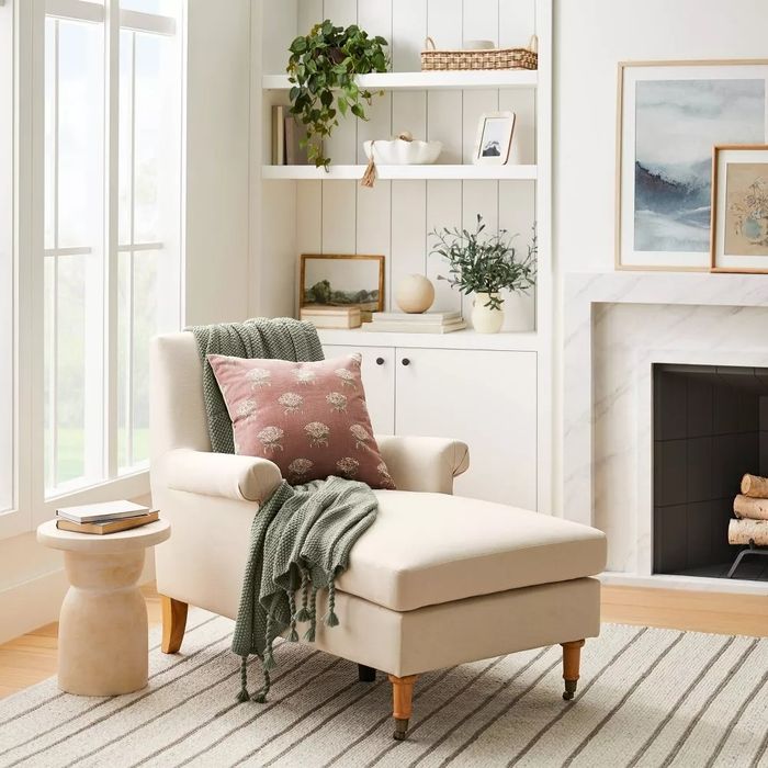 The chaise with a cozy pillow and blanket draped across it.