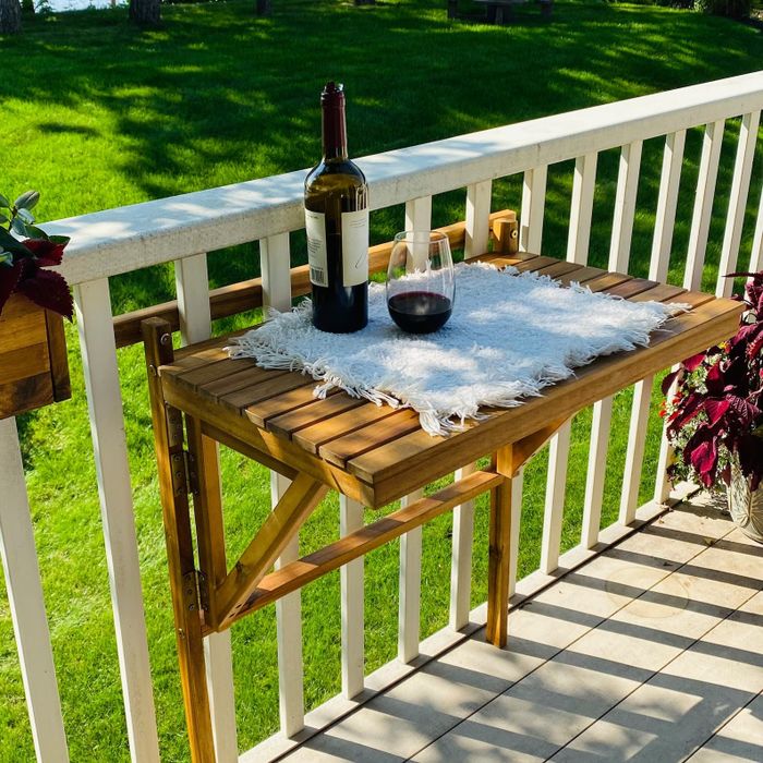 A folding wooden table attached to the balcony bars.
