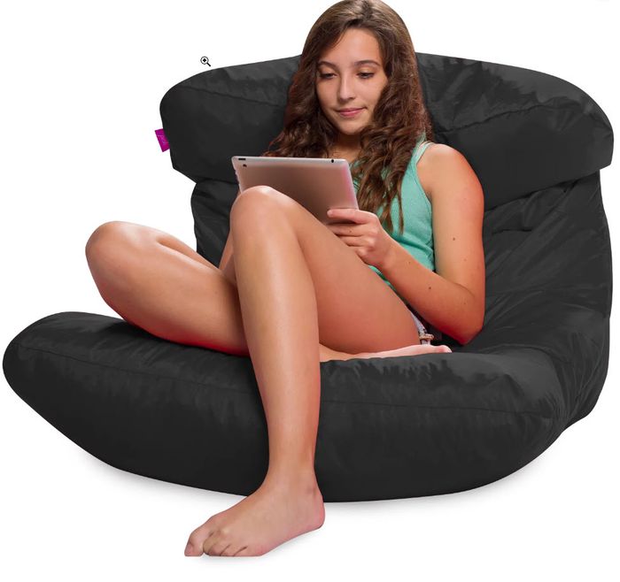 A woman sitting comfortably on a black beanbag chair on the floor.