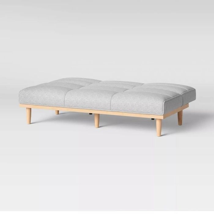 The gray convertible sofa bed fully extended into a flat position, ready to be used as a bed.